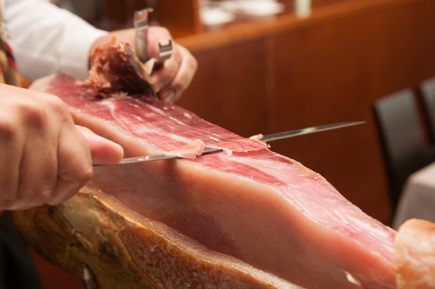 Cutting spanish ham and cured meat on a celebratory table