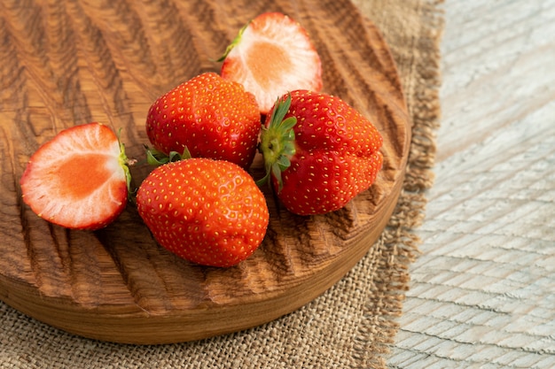 Cutting strawberries on wooden cutting board over grunge wooden table