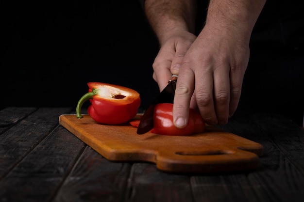 Cutting vegetables Male hands cutting sweet red pepper on cutting board