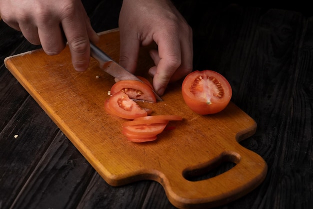 Cutting vegetables Male hands cutting tomatoes on a cutting board