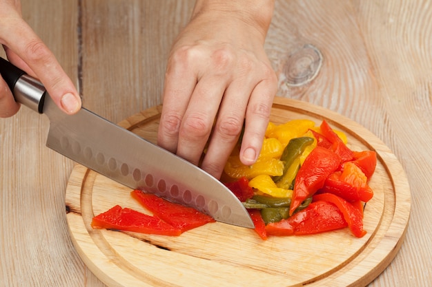 Cutting the vegetables with a kitchen knife on the board