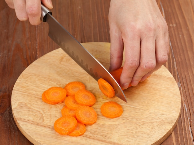 Cutting the vegetables with a kitchen knife on the board