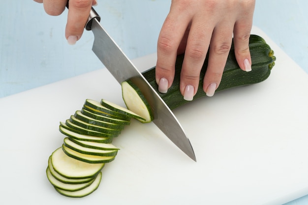 Cutting the vegetables with a kitchen knife on the board