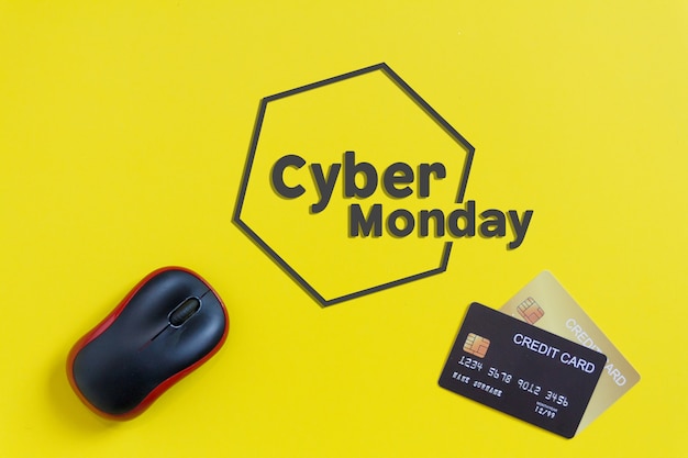 Cyber Monday text with Black mouse and credits cards on yellow paper background