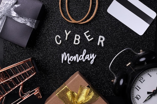 Cyber monday word surrounded by credit card, gift boxes, alarm clock, paper bag and mini trolley.