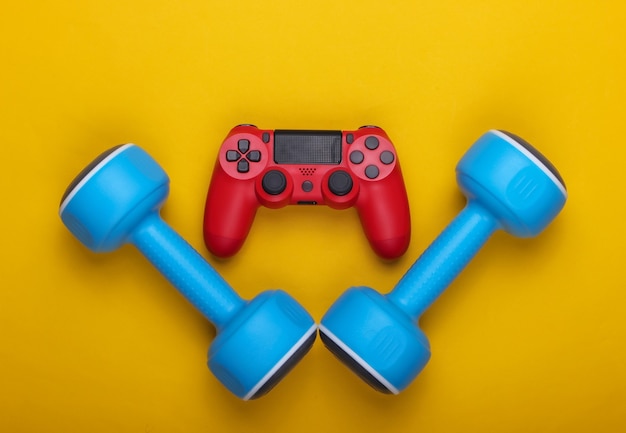 Cybersport. Sport and entertainment. Gamepad and dumbbell on a yellow