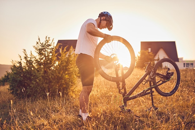 A cyclist is repairing a bicycle on a forest road at sunset. High quality photo