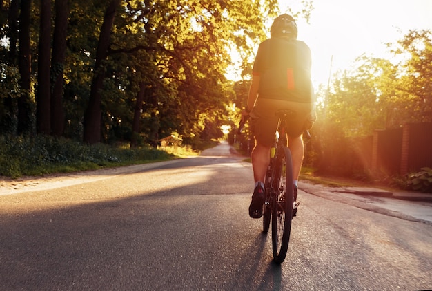 Cyclist is training on a bike outdoors on a summer evening at sunset.