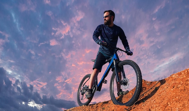 Cyclist in pants and fleece jacket on a modern hardtail bike with an suspension fork rides offroad