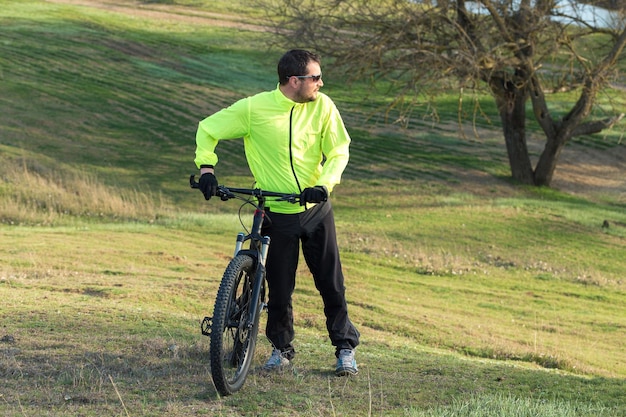 Cyclist in pants and green jacket on a modern carbon hardtail bike with an air suspension fork The guy on the top of the hill rides a bike