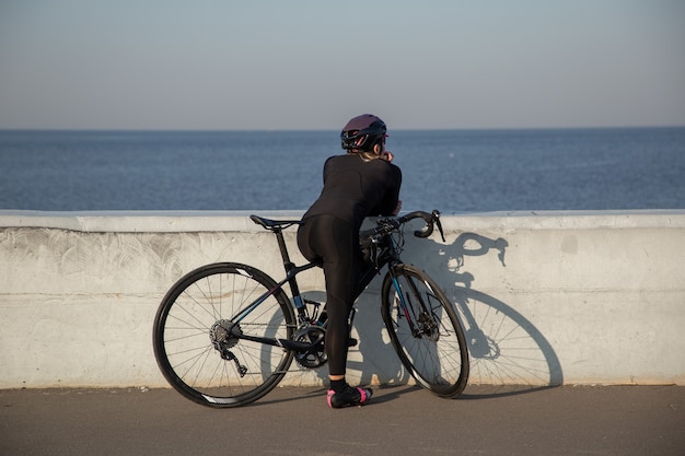 The cyclist rests on the embankment with looks towards the water