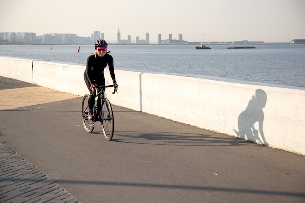 The cyclist rides along the embankment with the first rays of the sun