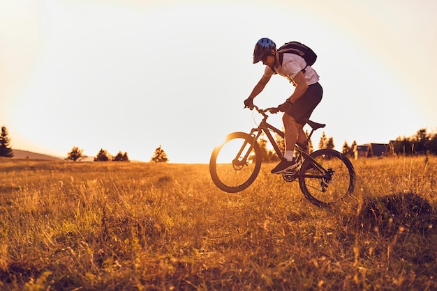 A cyclist rides a bike on forest roads at sunset