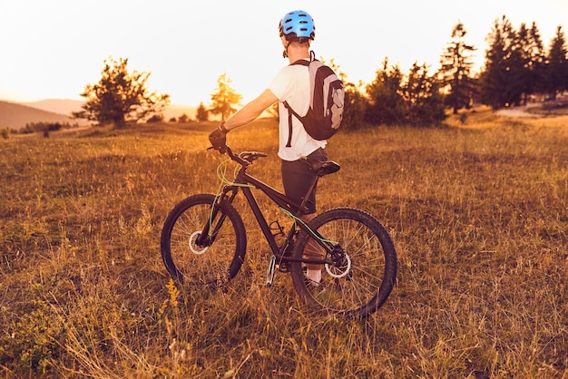 A cyclist rides a bike on forest roads at sunset