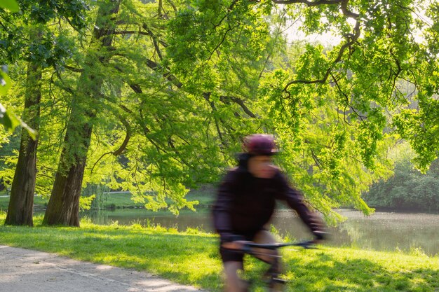 Cyclist riding in summer sunny park motion blur