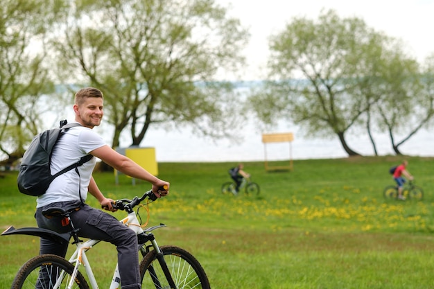 A cyclist with a backpack is standing on a bicycle in a clearing enjoying nature.