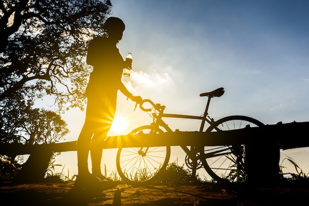 cyclist with a bike silhouette on sunset sky background