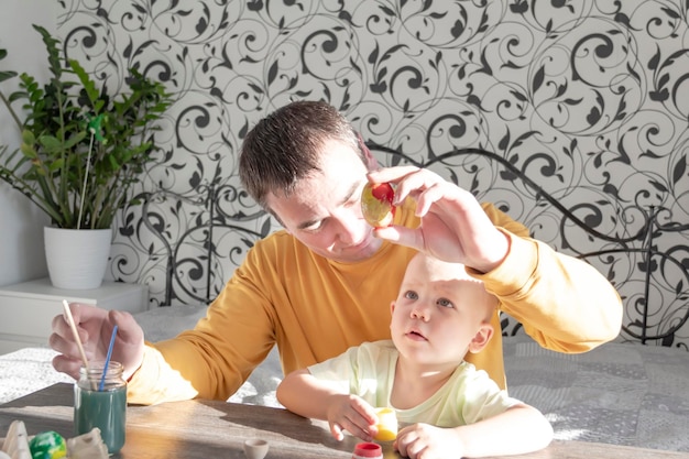 Dad and child paint eggs for Easter