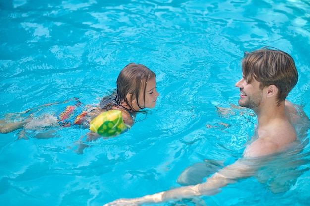 Dad and daughter swimming together in a swimming pool