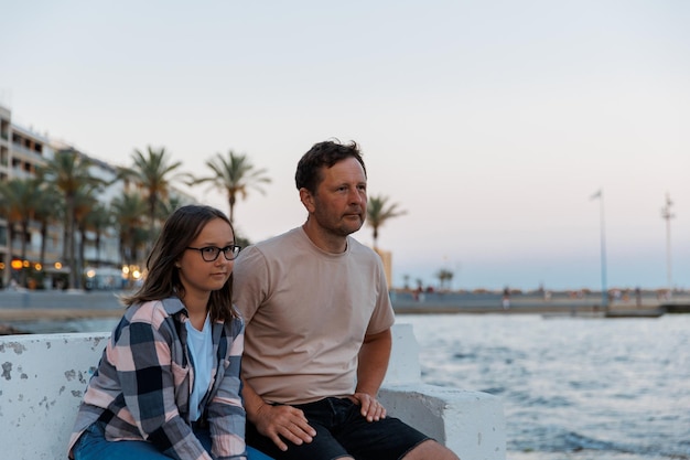 Dad and daughter walk in the evening around the city by the sea