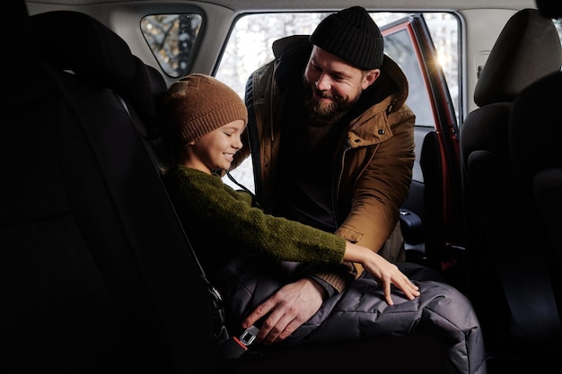 Dad fastening his daughter with seat belt before trip