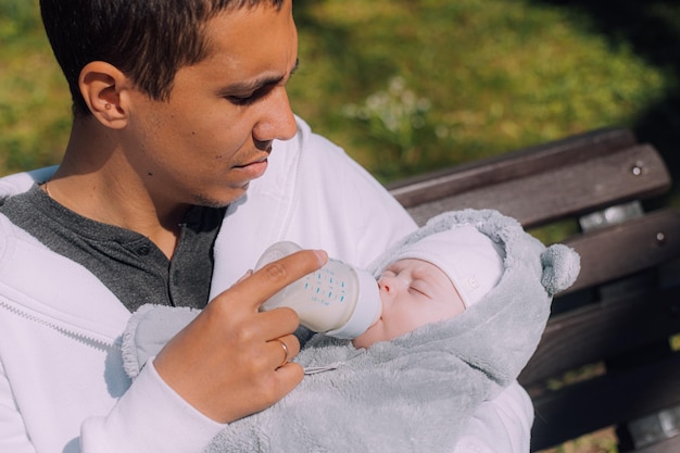 Dad feeds the baby from a bottle baby food fatherson relationship an article about helping moms