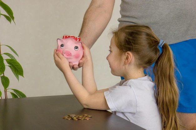 Dad gives little daughter a piggy bank