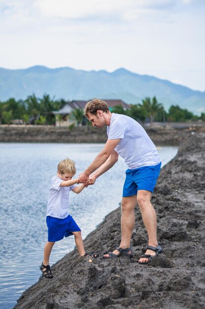 Dad helps son go down to lake water explains safety rules Family together walk play Home natural child education fathers day fatherly responsibilities influence on formation of son worldview