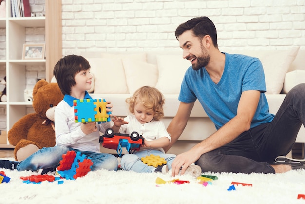 Dad and his two sons play toys at home.