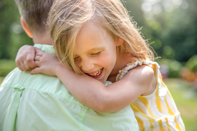 Photo dad holds his daughter in his arms happy girl laughs and hugs her father closeup happy family