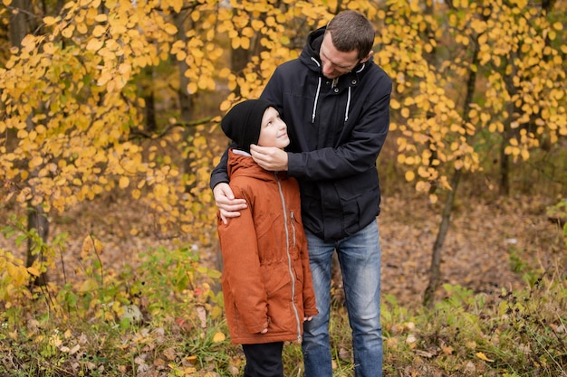 Dad hugs his son standing on the street in autumn