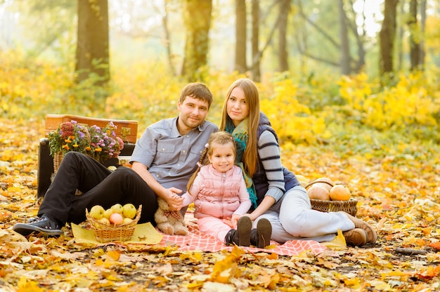 Dad, mom and daughter have fun together during an autumn picnic on the street.