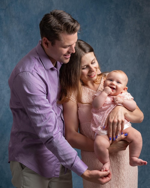 Dad mom hold their little daughter in their arms Portrait of a young family Tenderness and love of