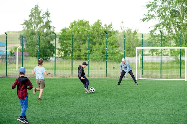 Dad plays football with children in the summer on the lawn