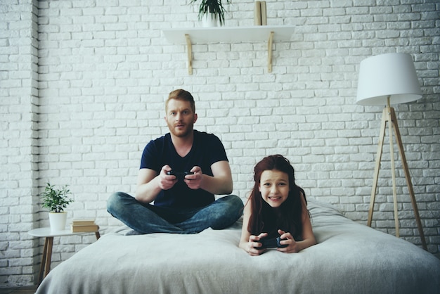 Dad plays joystick games with his little daughter.