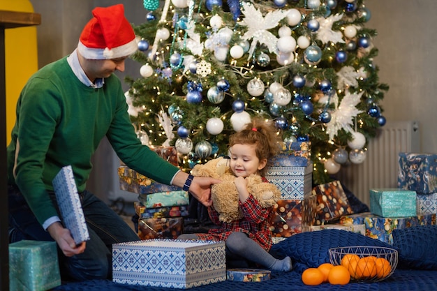 Dad in santa hat giving cute daughter gift for new year. father with child on christmas.