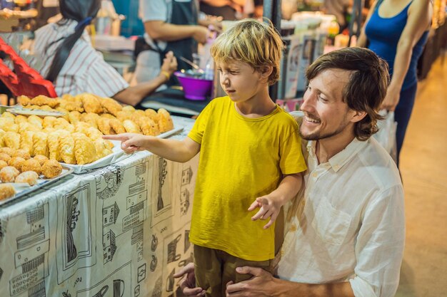 Dad and son are tourists on Walking street Asian food market