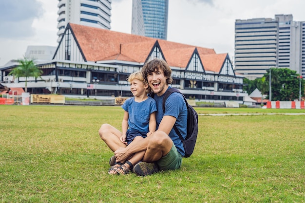 Dad and son on background of Merdeka square and Sultan Abdul Samad Building. Traveling with children concept