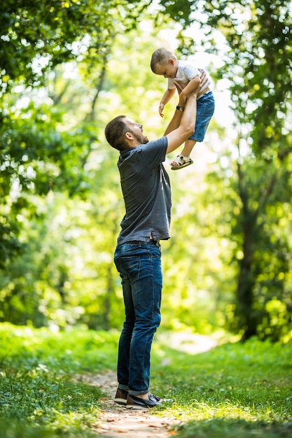 Dad and son having fun in park in summer day