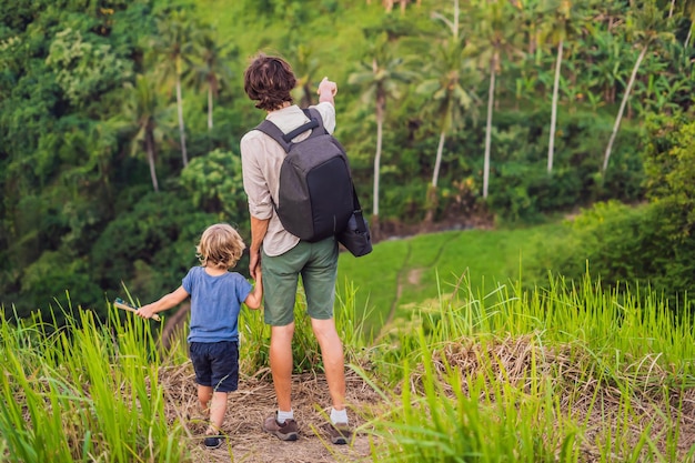 Dad and son travelers are looking at Beautiful of rice field among the dense jungle.