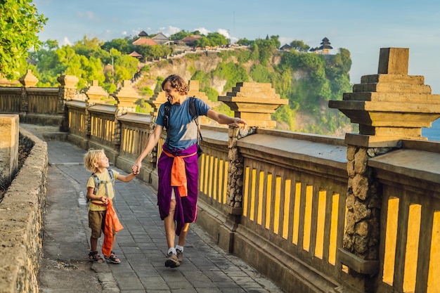 Dad and son travelers in Pura Luhur Uluwatu temple Bali Indonesia Amazing landscape  cliff with blue sky and sea Traveling with kids concept