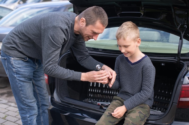 Dad teaches his cute son to use a car repair tool