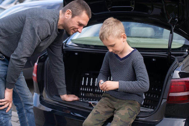 Dad teaches his cute son to use a car repair tool