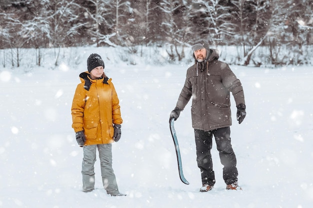 Dad teaches his daughter to ride a snow skate in a winter park family walk in the fresh air