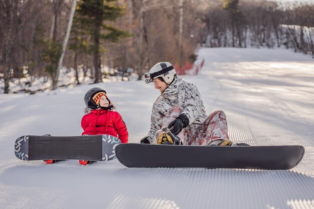 Dad teaches son snowboarding Activities for children in winter Children's winter sport Lifestyle