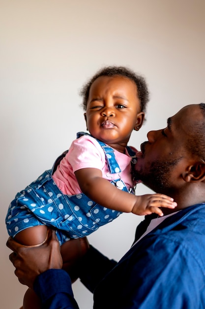 Dad with his 9 month old daughter in his arms looking at camera