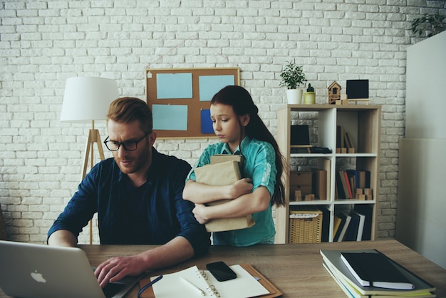 Dad works at computer and an upset girl stands nearby.