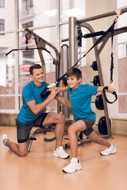 Dad and young son do exercise in the gym.