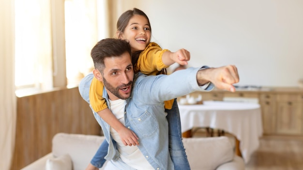 Daddy giving piggyback ride to daughter having fun at home