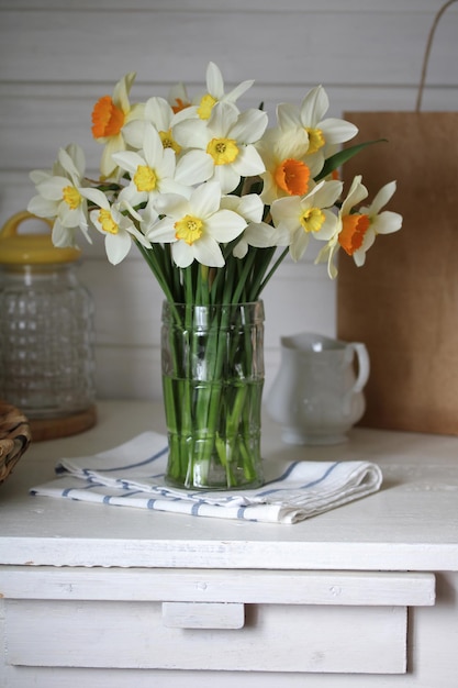 Daffodils in a glass vase in a rustic interior cottagecore